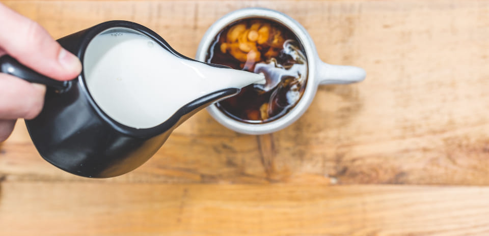 Whole milk poured from a black jug — the base for a homemade evaporated milk substitute